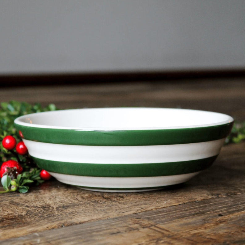 Cornishware donkergroen gestreepte kom van Cornishware Adder Green. op een houten tafel met kersttakken.