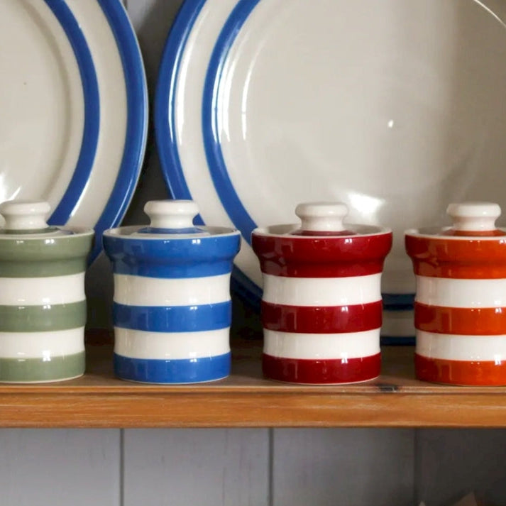 4 kruidenpotjes in verschillende kleuren op een plank in de keuken