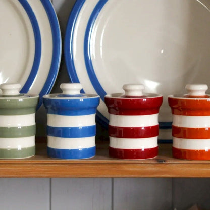 4 kruidenpotjes in verschillende kleuren op een plank in de keuken
