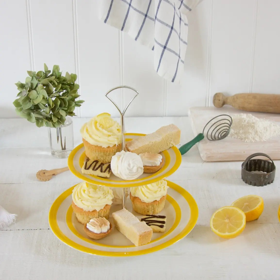 Cornishware Yellow etagere 2 laags op tafel met kleine gebakjes. Geel wit gestreept servies