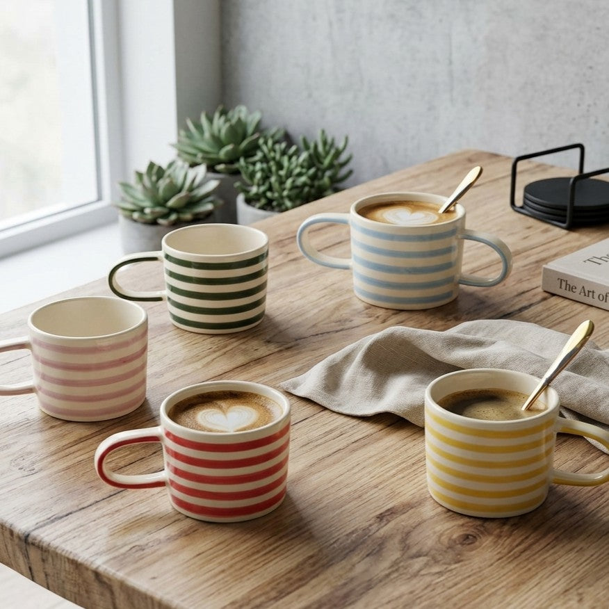 Sfeerbeeld van VT Wonen Stripes en Dots mokken in lila, geel, rood, blauw en groen, handgeschilderd stoneware op een tafel.